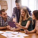 Grupo de jóvenes profesionales reunidos alrededor de una mesa de trabajo.
