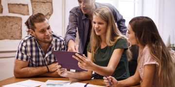 Grupo de jóvenes profesionales reunidos alrededor de una mesa de trabajo.