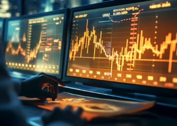 Un trader mira las pantallas de computadoras con graficos de precio en ellas.