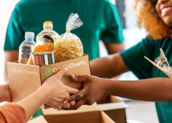 Un trabajador de CoinEx Charity entrega una caja de productos alimenticios a otra persona.