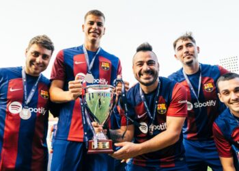 Cuatro jugadores del FC Barcelona reunidos sosteniendo un trofeo.