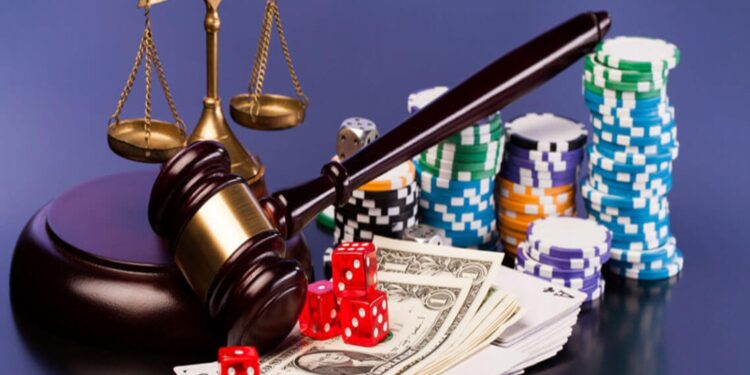 Fichas y dados de casino junto a un mazo de juez y la balanza de la justicia.