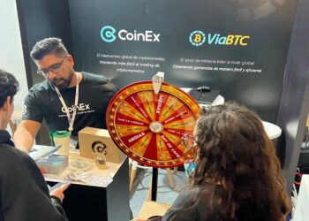 Tras personas conversando en el stand de CoinEx en la Blockchain Summit Latan 2024.