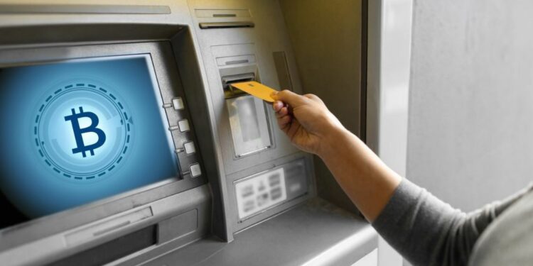 Una persona retirando dinero en efectivo de un cajero habilitado para bitcoin.