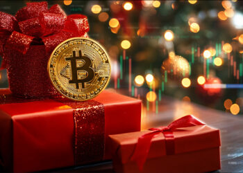 Cajas de regalo debajo de un arbolito navideño con una moneda de bitcoin encima.
