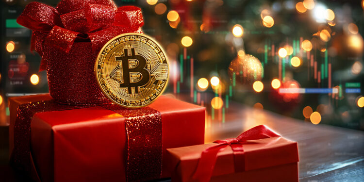 Cajas de regalo debajo de un arbolito navideño con una moneda de bitcoin encima.