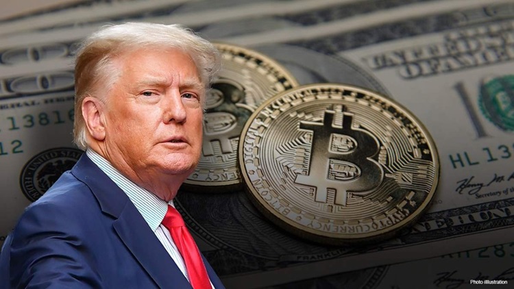 Donal Trump en traje azul y corbata roja con un par de monedas de bitcoin detrás.