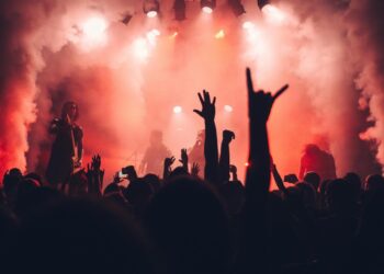 Una banda juvenil de músicos sobre el escenario con luces y humo sobre ellos.