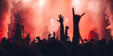 Una banda juvenil de músicos sobre el escenario con luces y humo sobre ellos.
