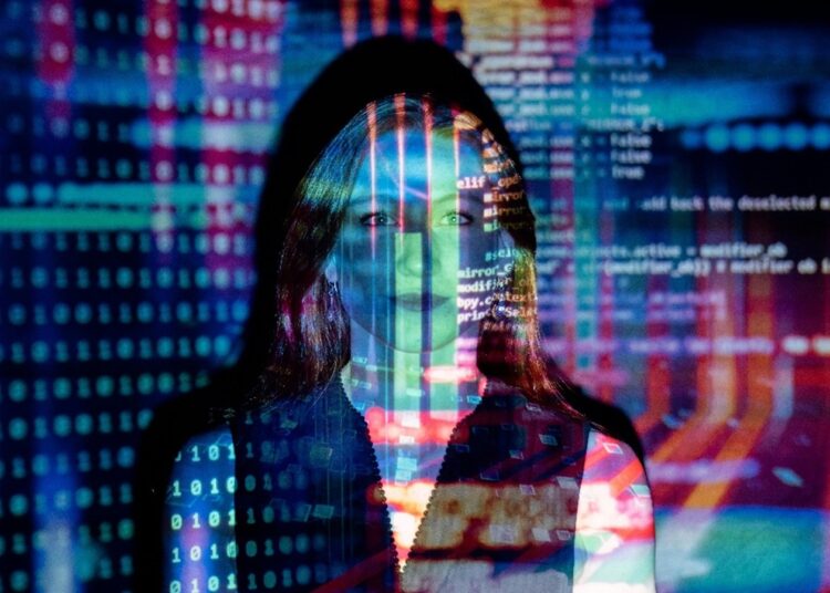 Mujer de pelo rubio reflejando las imágenes de una pantalla de computadora.