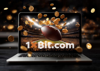 criptomonedas cayendo en frente computadora sobre mesa de madera, transmitiendo juego deportivo de futbol americano en pantalla y balon sobresaliendo de la pantalla