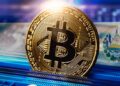 Una moneda de bitcoin frente a una bandera de El Salvador.