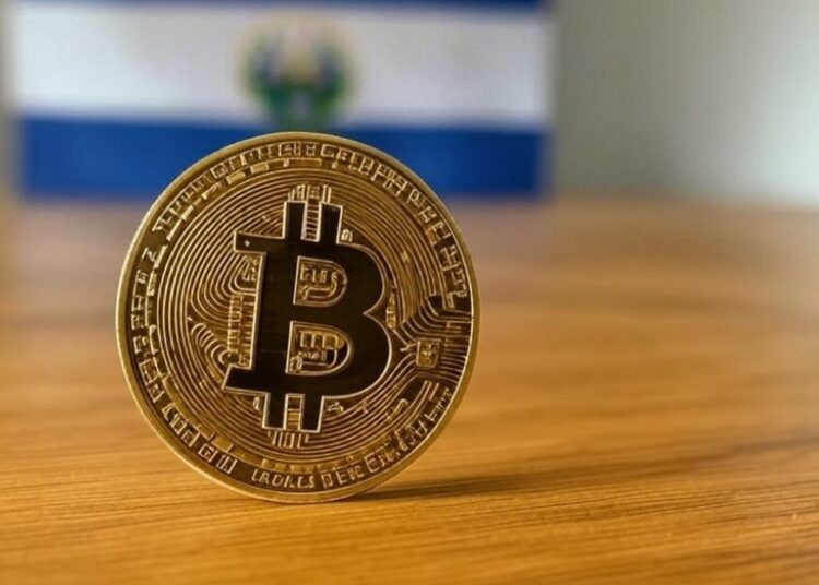 Una moneda física de bitcoin con la bandera azul y blanca de El Salvador de fondo