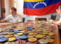 monedas sobre una mesa con una bandera de Venezuela de fondo.