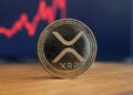 Una moneda con el logo de XRP apoyada sobre una mesa.