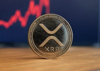 Una moneda con el logo de XRP apoyada sobre una mesa.