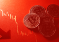 Monedas de bitcoin y un gráfico rojo representando caída de precios.