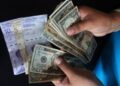 Una fotografía de alguien manejando dólares y bolívares en efectivo.