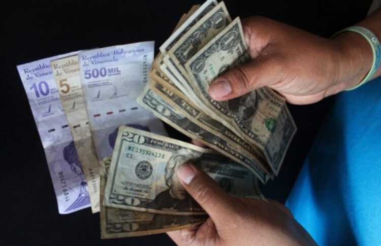 Una fotografía de alguien manejando dólares y bolívares en efectivo.