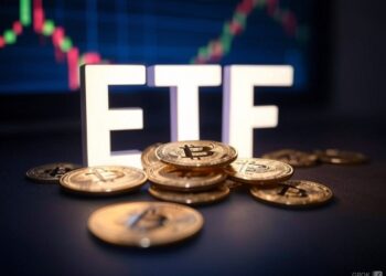 Una mesa con monedas de bitcoin y las letras ETF em blanco con un fondo de un gráfico.
