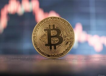 moneda de bitcoin sobre una mesa con un gráfico de precios en el fondo.