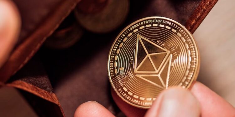 Una mano sosteniendo una moneda de ethereum cerca de una billetera