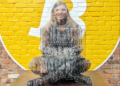 Una persona reflejada a través de la estatua de Satoshi Nakamoto en Tokio