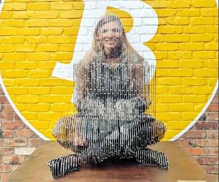 Una persona reflejada a través de la estatua de Satoshi Nakamoto en Tokio