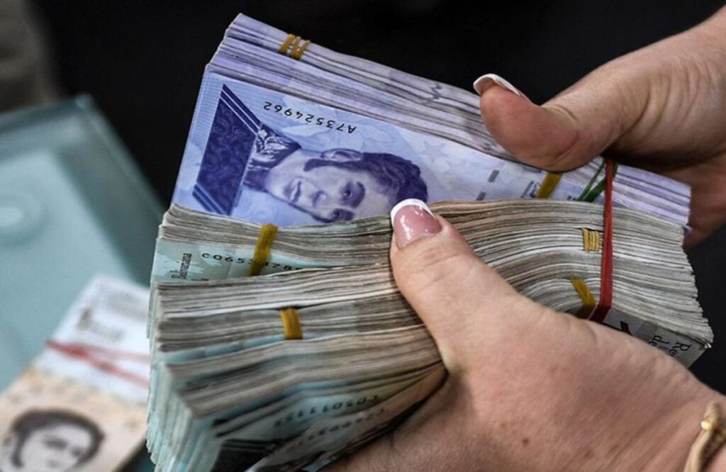 Fajo de billetes en bolívares en la mano de una mujer.
