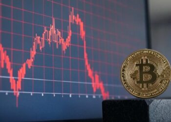 Gráfico de acciones en rojo y una moneda de bitcoin al lado