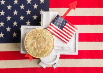 Moneda de bitcoin arriba de la Casa Blanca, sobre una bandera de Estados Unidos.