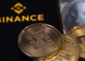teléfono con el logo de Binance y una moneda de BNB.
