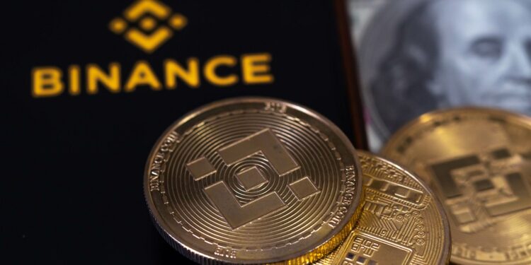 teléfono con el logo de Binance y una moneda de BNB.