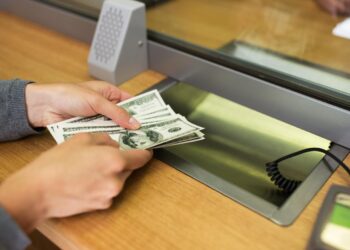 Imagen de una persona con billetes de dólares en una agencia bancaria.