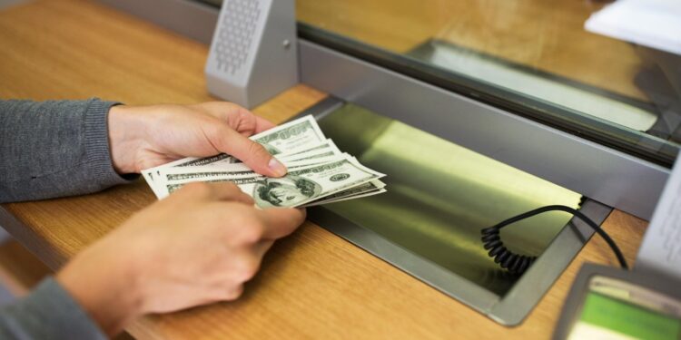 Imagen de una persona con billetes de dólares en una agencia bancaria.