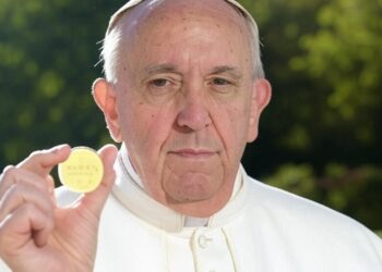 El Papa Francisco muestra una moneda.