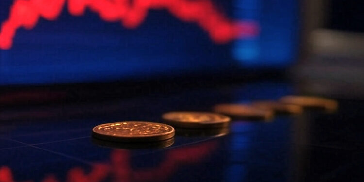 monedas alineadas sobre una pantalla con grafico de precio bajista en rojo en pantalla de fondo
