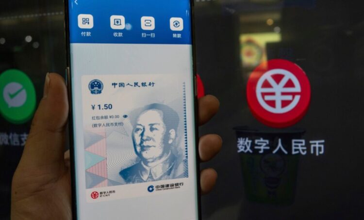 Fotografía de un teléfono con la aplicación del yuan digital y un negocio que acepta esa moneda.