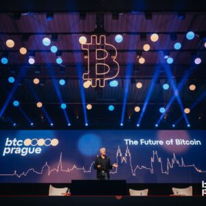 Escenario principal de BTC Prague con un ponente hablando bajo luces azules y naranjas, el logo de Bitcoin colgando y la frase "The Future of Bitcoin" en pantalla.
