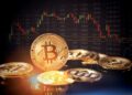 Monedas físicas de bitcoin sobre una superficie reflejante, con un gráfico de velas japonesas de fondo que muestra la volatilidad del mercado de criptomonedas.