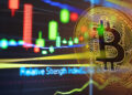 moneda de bitcoin sobre pantalla con grafico de precio digital