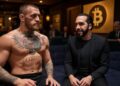 Connor McGregor sentado junto a Nayib Bukele con un logo de Bitcoin al fondo.