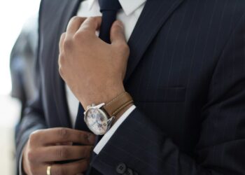 Torso de un hombre en traje ajustándose la corbata,