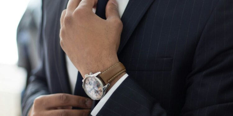 Torso de un hombre en traje ajustándose la corbata,
