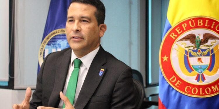 Luis Eduardo Llinás en su oficina junto con una badera de Colombia.