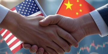 Manos estrechándose con las banderas de EE. UU. y China en el fondo.
