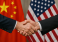 Apretón de manos, delante de las banderas de Estados Unidos y China.