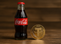 Una botella de Coca-Cola y una moneda física de USDT.