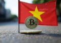 Una bandera de Vietman junto a una moneda de bitcoin.
