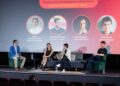 Panel de discusión en un evento de blockchain con cuatro oradores y un moderador.